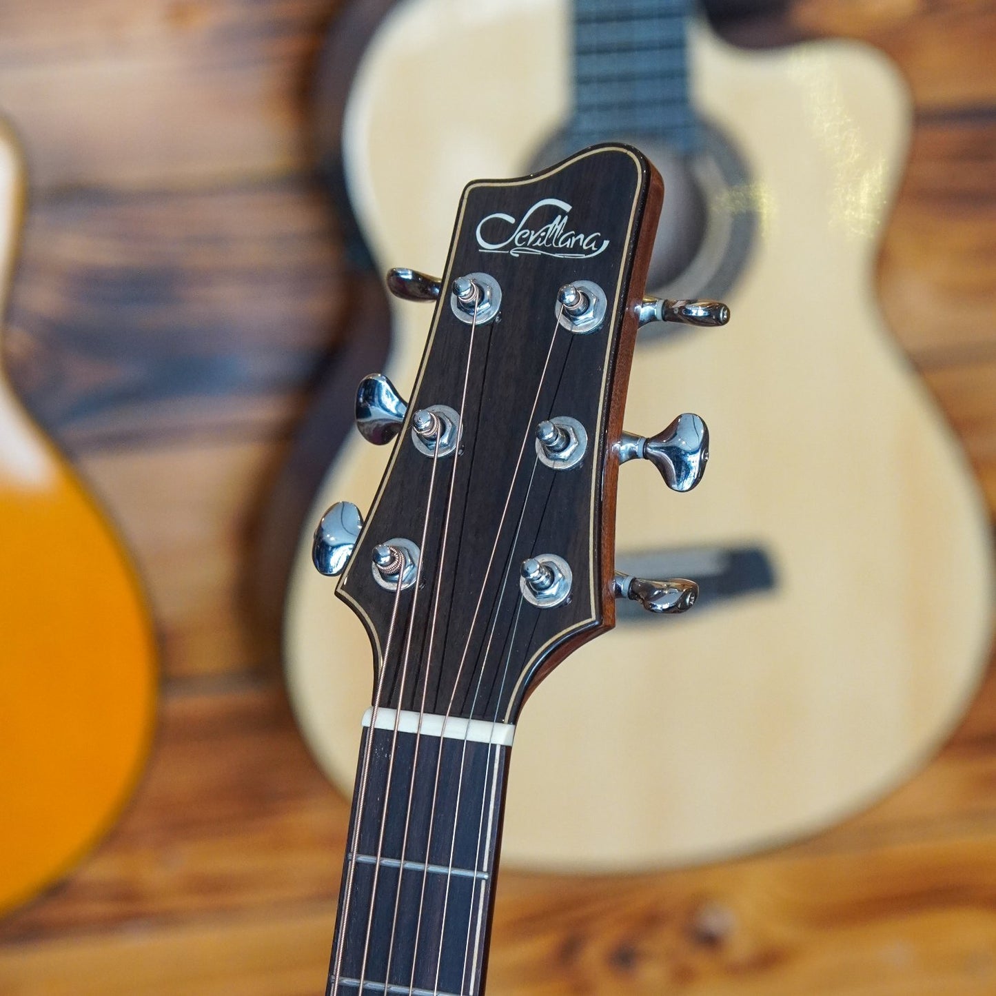 Front of the headstock of an acoustic guitar, showing tuning pegs and wood grain