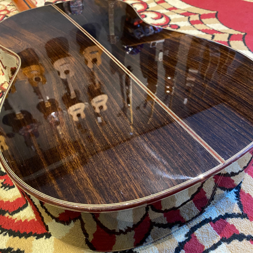 Close-up of a guitar's wooden body on a patterned rug