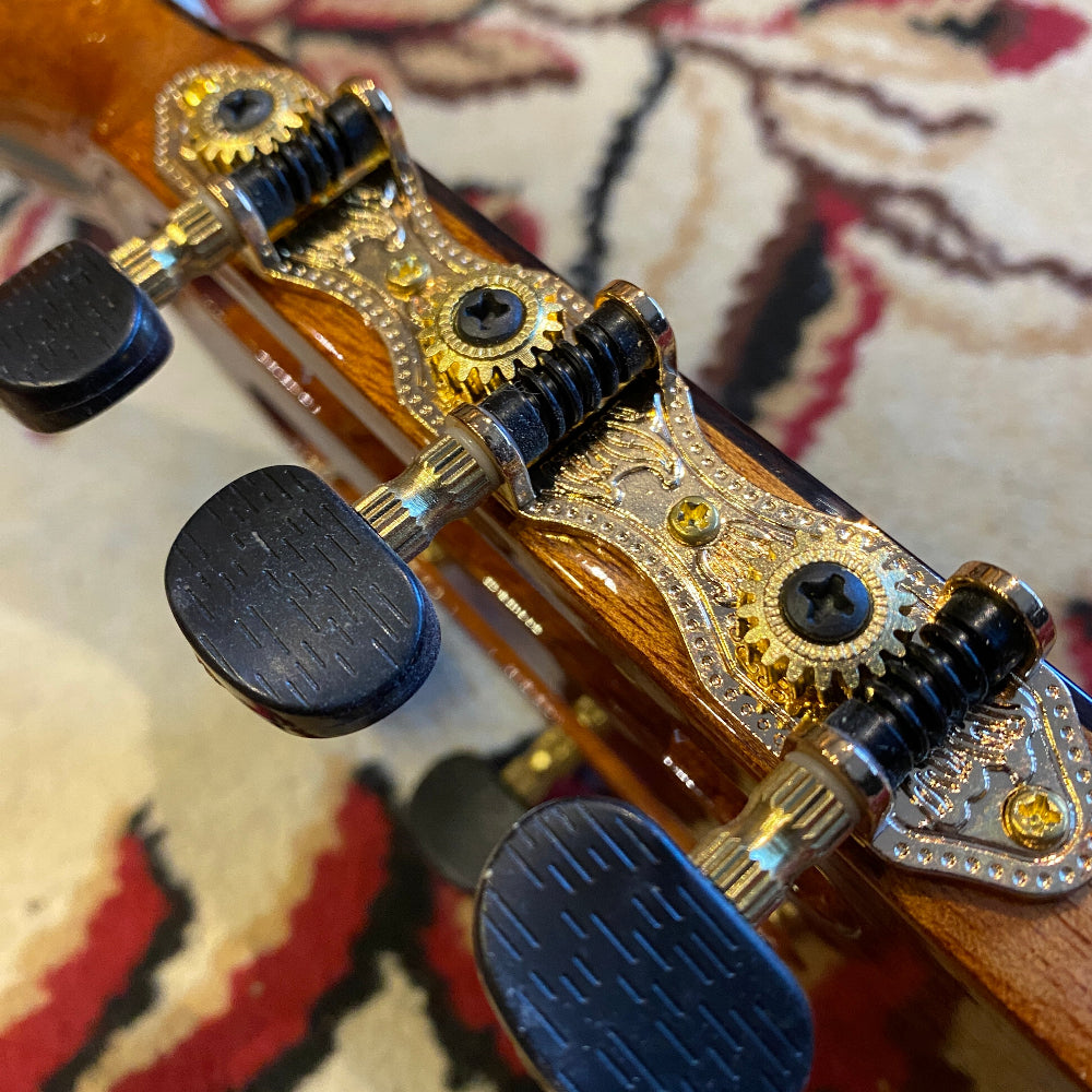 Close-up of a guitar's tuning pegs with wooden and metal details.