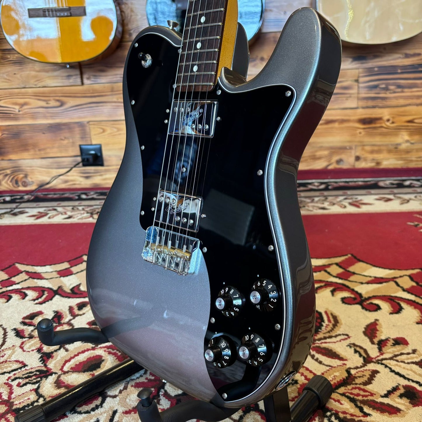 The front body of a Fender American Pro II Telecaster Deluxe electric guitar on a stand, showing its dual humbuckers and classic Telecaster shape.