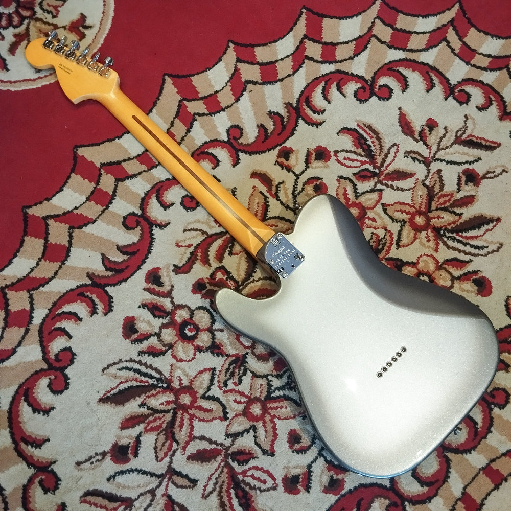 The back of a Fender American Pro II Telecaster Deluxe electric guitar lying on a red carpet, showing the neck joint and smooth body finish.