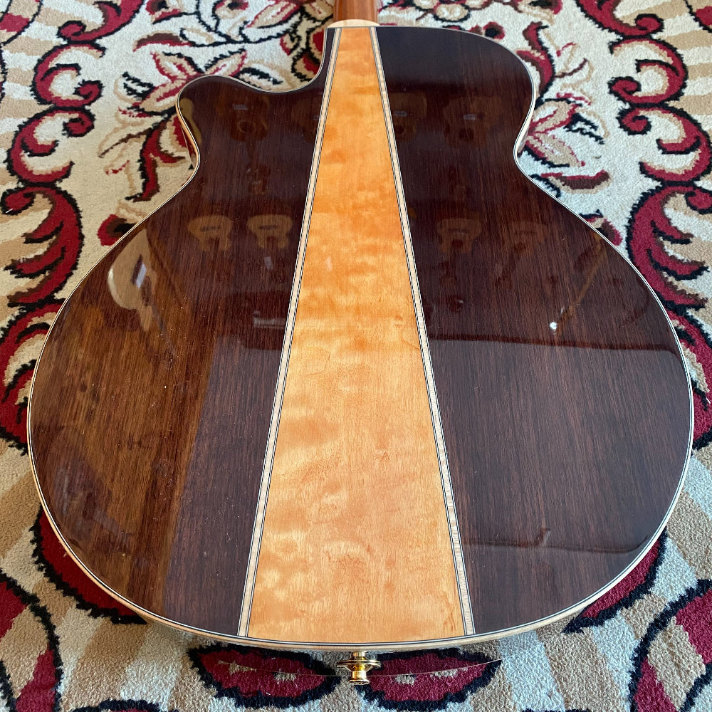 Wooden instrument with a dark brown and light brown design on a patterned rug