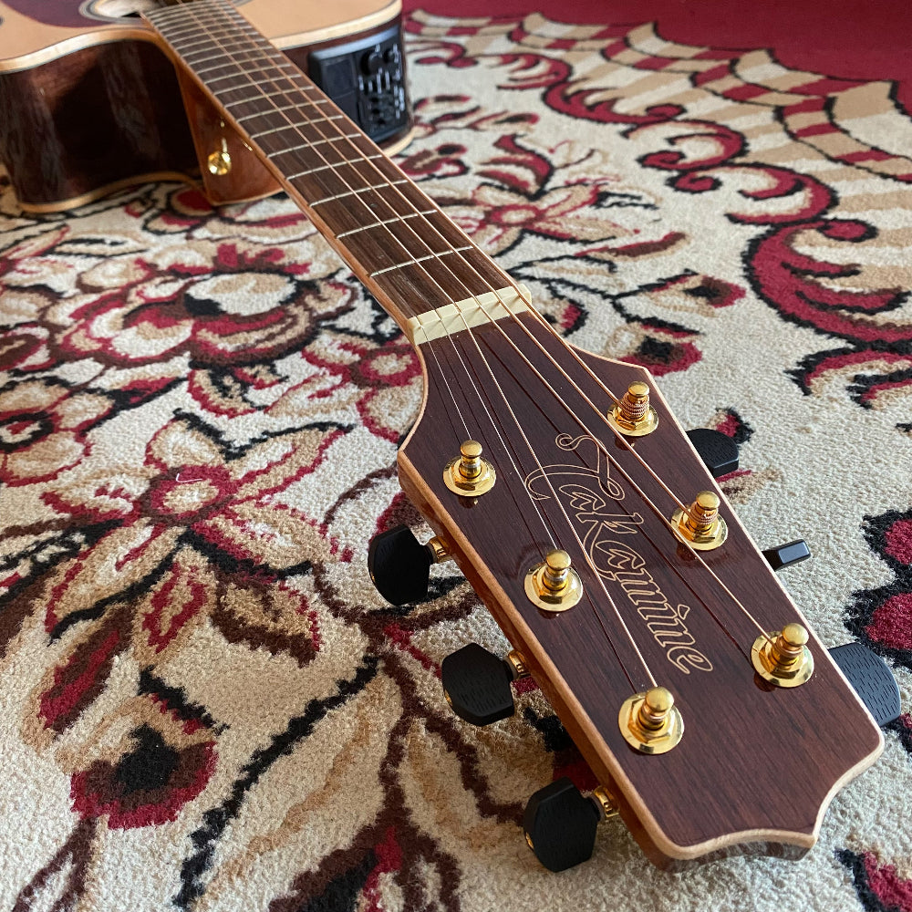 Close-up of a guitar neck and headstock on a patterned rug