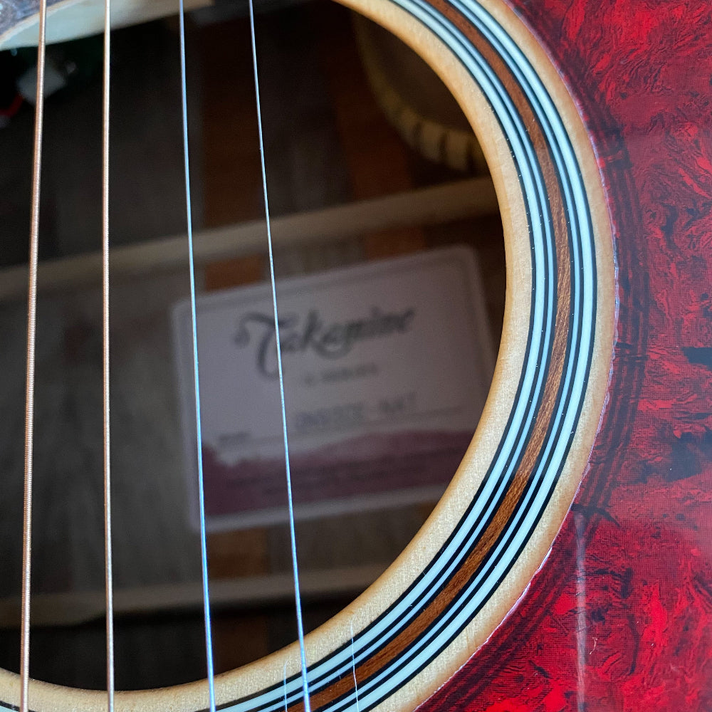 Close-up of a guitar's soundhole with 'Takamine' branding.