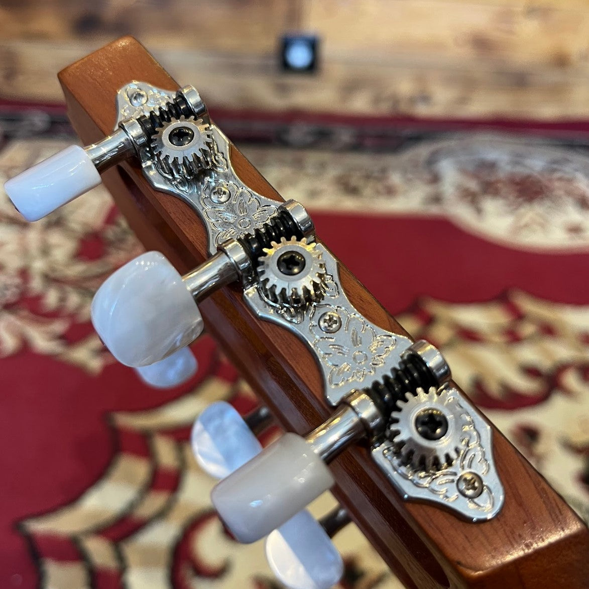 Side view of the headstock of a Taylor Academy 12e Nylon acoustic guitar, showing the slotted design and tuning pegs.