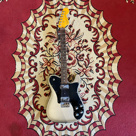 A Fender American Pro II Telecaster Deluxe electric guitar resting on a red carpet.
