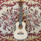 A concert/tenor size electric ukulele with a solid Sitka Spruce top, Rosewood back, sides, and neck, placed on a patterned fabric surface.