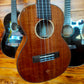  Close-up of the body of a ukulele, showing the sound hole, wooden grain, and bridge
