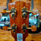 Back of the headstock of a ukulele, showing the tuning pegs and wood grain.