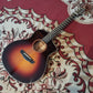 Acoustic guitar with a natural wood finish, placed on a patterned red and white background.