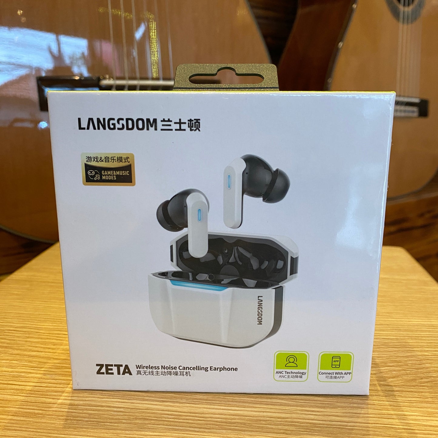Box of LANGDOOM ZETA earbuds on a wooden surface with a guitar in the background