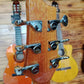 Back of the headstock of an acoustic guitar, showing tuning pegs and wood grain.