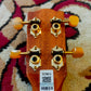 Back of the headstock of a ukulele showing tuning pegs and a barcode brand sticker.