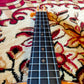 Fretboard of a ukulele showing the frets, dot inlays, and smooth wooden surface