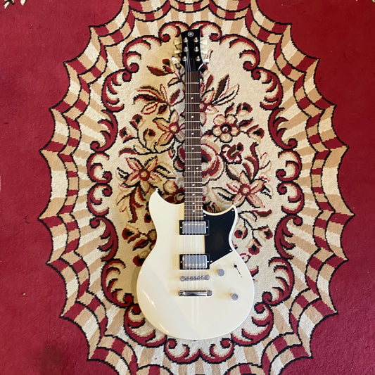 White guitar Yamaha Revstar on a decorative red and beige rug