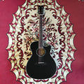 A Cetta OM28CE acoustic guitar resting on a red carpet, featuring a black wood finish and cutaway design.