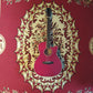 A Cetta OM28CE acoustic guitar resting on a red carpet, featuring a red wood finish and cutaway design.