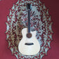 A Cetta OM28CE acoustic guitar resting on a red carpet, featuring a natural wood finish and cutaway design.